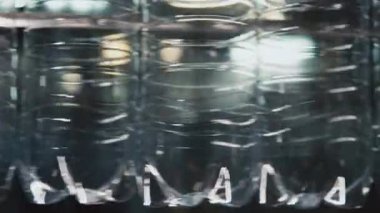 Kimse içecek fabrikasındaki konveyör hattında ilerleyen boş plastik şişelerin yakın çekimini bıçaklamaz.