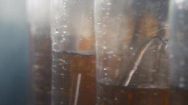 Kimse içecek fabrikasında şeffaf PET şişelerini turuncu karbonatlı içecekle dolduran dönen şişe makinesine yakın çekim yapmaz.