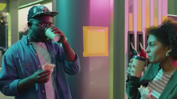 美国黑人青年男子在夜间休息站和在霓虹灯加油站小憩时与黑人女友交谈的镜头 — 图库视频影像