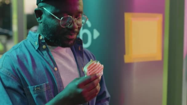 Incline Close Afro Americano Gen Guy Óculos Boné Comendo Sanduíche — Vídeo de Stock