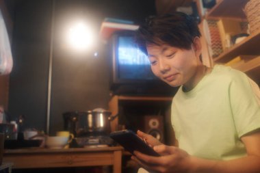 Genç Çinli bir kadın internetten ilginç videolar izliyor ya da sosyal ağlardaki paylaşımlara bakıp küçük bir dairede yemek yiyor.