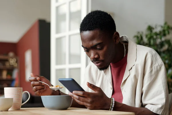 Giovane Uomo Afroamericano Mangiare Cornflakes Con Latte Ciotola Sms Smartphone — Foto Stock