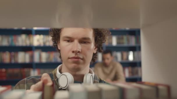 머리를 코카서스 학생의 클로즈업 선택적인 도서관에서 주위에 헤드폰 선반에서 — 비디오
