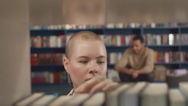 도서관에서 책장에 머리를 코카서스 소녀의 클로즈업 선택적인 선반에서 지나가는 배경에서 — 비디오