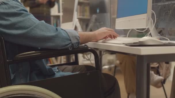 大学图书馆台式机前坐在轮椅上 键盘上打字的无法辨认的残疾男子的双手和中间部分中特写 — 图库视频影像