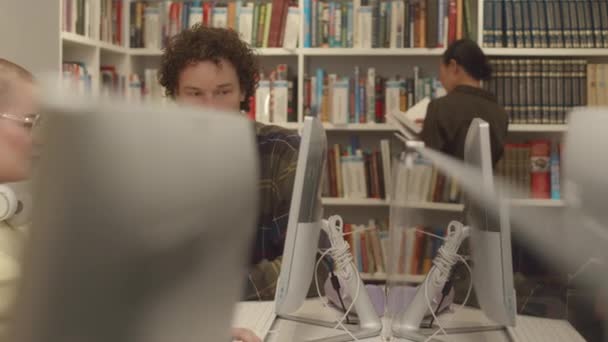 若い白人男性と女性がデスクトップコンピュータの前に座ってインターネットを閲覧し 割り当てを準備し タスクを議論し メモを取る — ストック動画