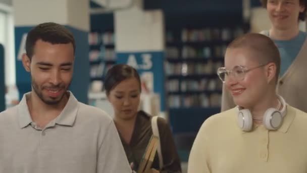 쾌활한 남성과 그룹의 도서관 쌍으로 활기찬 대화와 미소를가지고 — 비디오