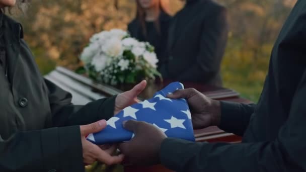 葬儀の外で亡くなった軍人の母コーカサスに米国国旗を渡す認識できない男のサイド傾斜クローズアップ — ストック動画