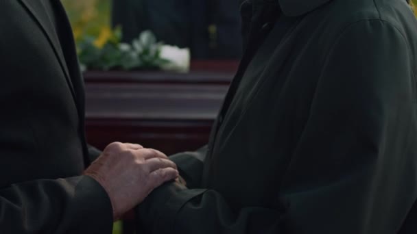 シニア未確認の男性のサイド傾斜クローズアップ 悲しみのシニアマザーの手をストローキングし 屋外葬儀で彼女を解放 — ストック動画