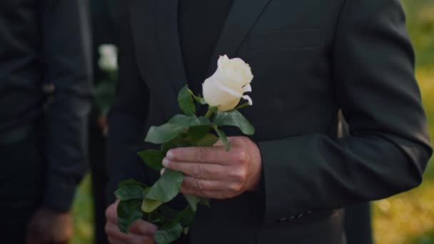 白种人老年鳏夫在公墓为他已故的妻子举行的告别葬礼上 手持一朵白玫瑰的特写特写 — 图库视频影像