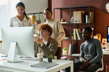 Yeni proje noktalarının sunumu sırasında bilgisayar ekranına bakan kendinden emin genç erkek borsacı ve bir grup meslektaşı