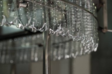 Büyük şişelenmiş su fabrikasının içinde dönen büyük sanayi makinesinde dönen boş temiz plastik şişelerin alt kısmı.