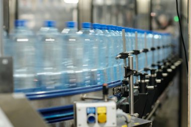 Filtrelenmiş ya da karbonatlı maden suyu içeren sıra sıra hareket eden plastik şişeli fabrika robotik taşıyıcı bandı.