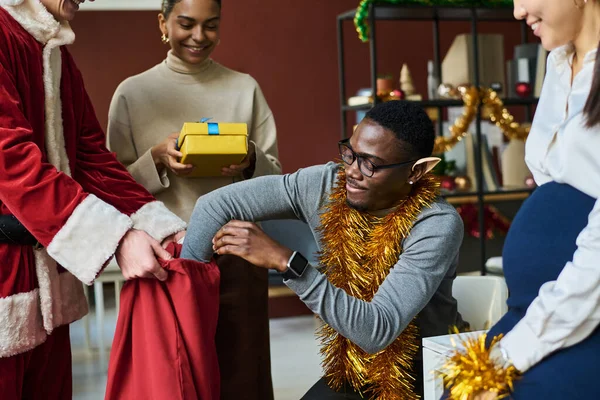 Νεαρός Αφροαμερικανός Υπάλληλος Γραφείου Βάζει Χέρι Κόκκινο Σάκο Χριστουγεννιάτικα Δώρα — Φωτογραφία Αρχείου