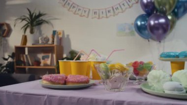 Kimse evde çocukların doğum günü partisi için bir masa dolusu donut, marşmelov ve farklı şekerlemeler görüntülemiyor.