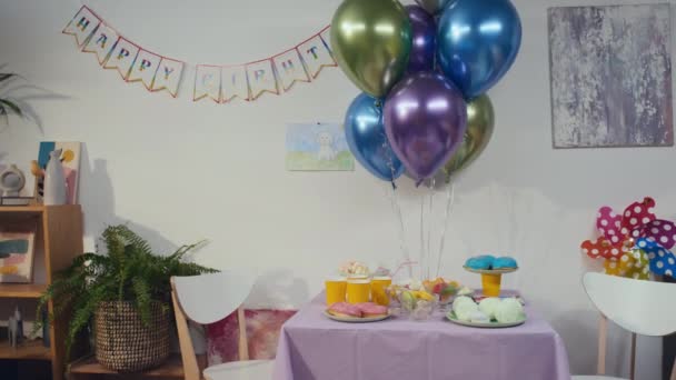 子供の誕生日に飾られたさまざまなお菓子と風船 ガーランド テーブル付きの空の部屋の映像はありません — ストック動画