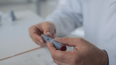Klinikteki masada oturan, elinde insülin kalemi tutan ve diyabete sahip kişilere danışmanlık yaparken kullandığı metodu gösteren isimsiz tıp doktorunun yakın plan fotoğrafları.
