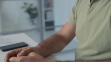 Gri saçlı, sakallı, gözlüklü, yorgun orta yaşlı beyaz bir adamın ellerini ve yüzünü yakından çekerek pratisyen hekime baş ağrısı ve beyin bulantısından yakınıyor.