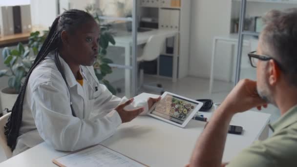 Середній Знімок Молодого Афроамериканського Лікаря Білому Пальто Сидить Столом Клініці — стокове відео