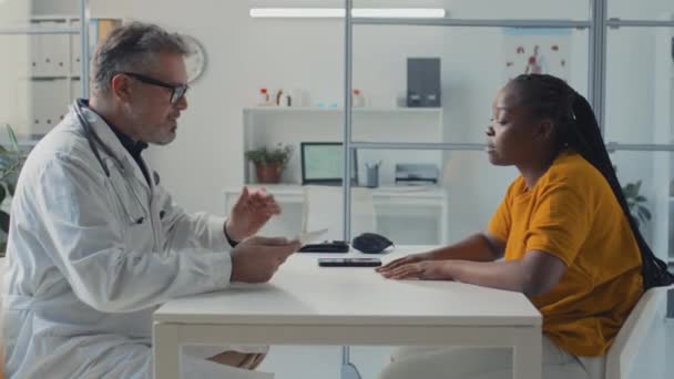 Średni Strzał Boku Dojrzałego Białego Lekarza Siedzącego Przy Stole Afroamerykańską — Wideo stockowe