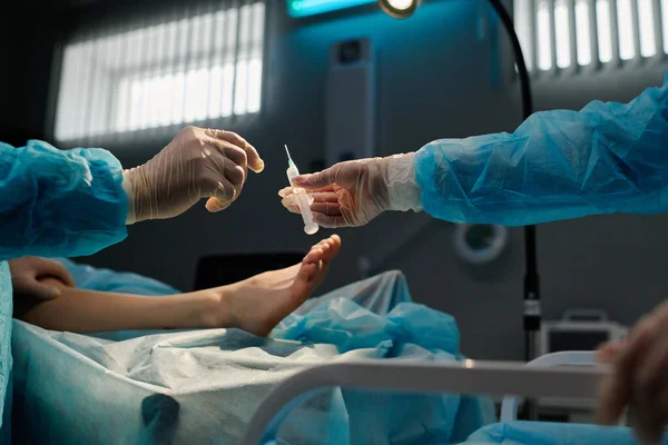 手術テーブルの上に横たわっている患者の足に対する手術中に局所麻酔で注射する外科医の手袋 — ストック写真