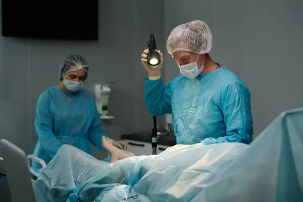 外科手术前男性外科医生在手术台旁放置餐巾纸时调整灯 — 图库照片