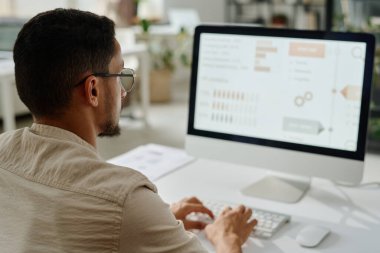 Genç CEO ya da girişimci bilgisayar ekranına bakıyor ve verileri analiz ediyor ya da işyerinde otururken iş düzenliyor