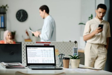 Ekranda sonuçların özeti olan dizüstü bilgisayar genç çalışanlara karşı analistin ya da komisyoncunun işyeri olarak duruyor.