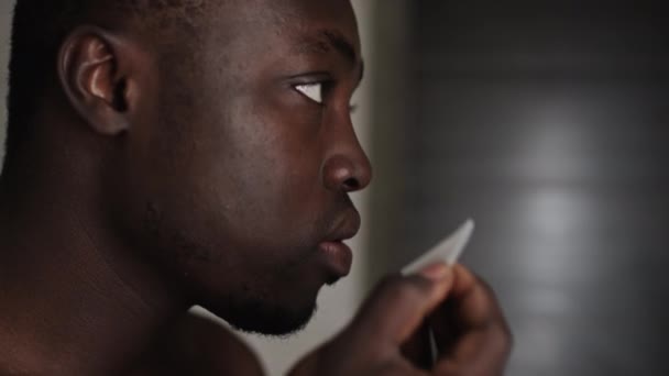 在家里做日常个人护理的同时 小心地使用化妆品眼罩 拍摄非洲裔美国年轻人剪短头发和胡子的特写镜头 — 图库视频影像