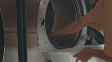 Orta bölüm, çamaşır makinesinden temiz çamaşırları çıkarıp çamaşırhanedeki modern çamaşır kurutma makinesine yükleyen kimliği belirsiz bir kadının görüntülerini kaydetti.