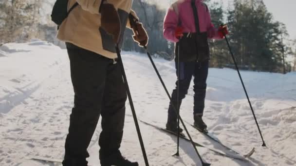 冬の森の旅に出る準備をしている間 スキーブーツを結合する厚い灰色のひげを持つ上級白人男性の中型傾斜ショット そして笑顔の女性コンパニオンウォッチング — ストック動画