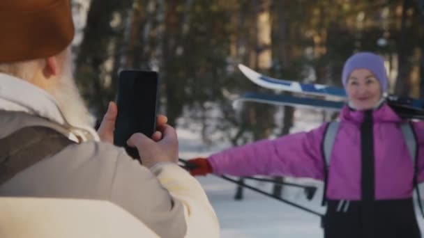 Средний Плечом Снимок Пожилого Человека Стоящего Зимнем Лесу Фотографирующего Смартфон — стоковое видео