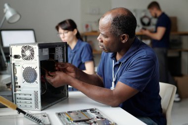 Profesyonel yetişkin teknisyen, tamirhanede çalışıyor ve parçalanmış bilgisayar işlemcisinin teknik sorunlarını tespit ediyor.