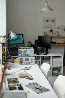 Parçalanmış dizüstü bilgisayar, elektrikli el aleti, bozuk akıllı telefon ve bilgisayar donanımı tamirhanedeki tamircinin iş yerinde.