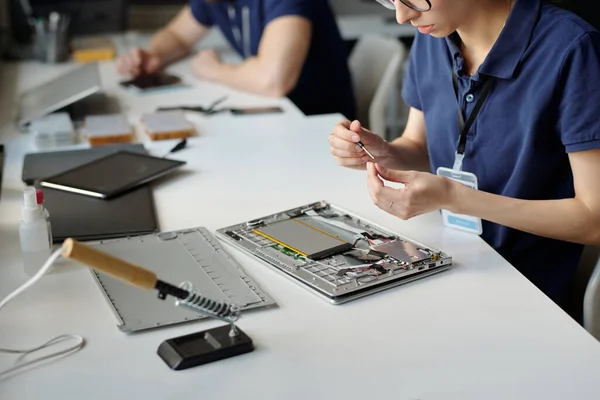 デスクで座っている修理工場の若い女性労働者の手と同僚のチェック電話に対する分解されたラップトップの小さな詳細を修正 — ストック写真