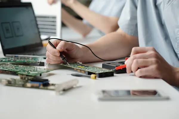 コンピュータマザーボードのチェックと修理中に電動ハンドツールを使用したトラブルシューティングサービスセンターの若手労働者の手 — ストック写真