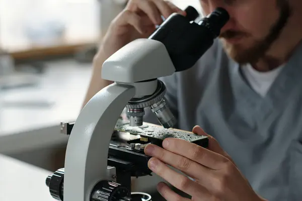 Anakart Detaylarına Mikroskop Merceğiyle Bakarken Laboratuvarda Kameranın Önünde Oturan Genç — Stok fotoğraf