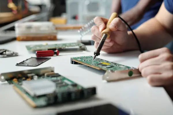 サービス センターのコンピュータ プロセッサのマザーボードを修理伝達装置が付いている若い認識できない技術者かエンジニアの手 — ストック写真