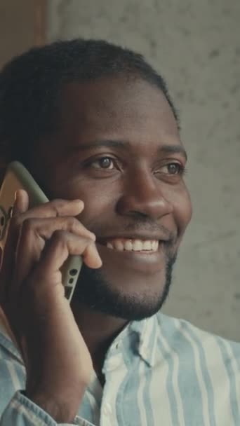 現代のカフェで携帯電話で話している陽気なアフリカ系アメリカ人の実業家の垂直閉鎖 — ストック動画