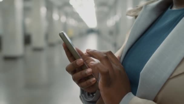 スマートフォンにメッセージを送信し 軽い地下鉄駅で電車を待っている周りを見ながらメガネでアフリカ系アメリカ人のビジネス女性の傾斜側のクローズアップ — ストック動画