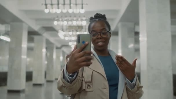 モバイルスクリーンを見て ビデオを録画したり 軽い地下鉄でビデオ通話会話をしたりしながらメガネで黒人女性のメディア映像 — ストック動画