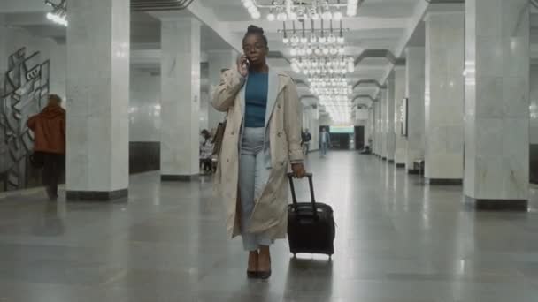 트렌치 코트에서 아프리카계 미국인 비즈니스 숙녀의 동영상을 바퀴에 가방과 스마트 — 비디오