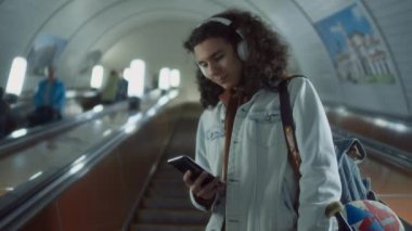 Kafkasyalı Z jeneratörlü adamın telefon ekranına bakarken ve kaykay tutarken yeraltı çıkışına tırmandığı düşük açılı görüntüler.