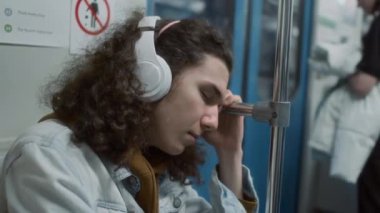 Aşırı çalışan Kafkasyalı Z gen öğrencisinin yakın plan görüntüleri. Metro metrosunda eve giderken kulaklıkla ses dinlerken uyuyakalıyorlar.