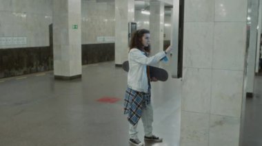 Kafkas gen Z patencisinin dijital ekranlı döşeme direğinin yanında duran ve boş lobideki metro transit haritasını kontrol eden yan görüntüsü