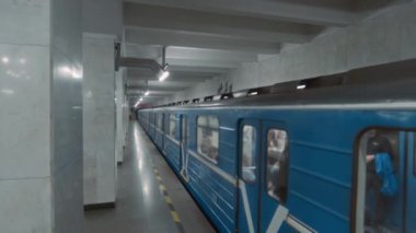 Boş metro peronundan ayrılan yolcularla dolu modern metro treninin yan görüntüleri.