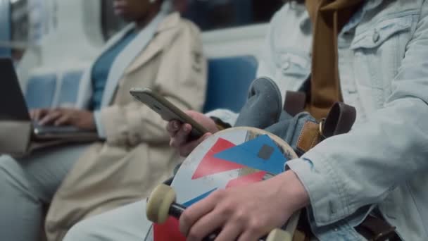 サイド傾斜コーカサス遺伝子Z男は 携帯電話を使用してヘッドセットで音楽を聞いている間 スケートボードでチューブ公共電車で移動します — ストック動画