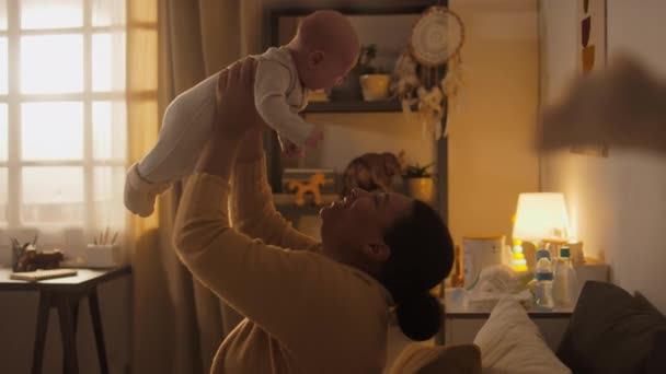 3ヶ月の赤ちゃんの息子をボディスーツで抱きしめ キスし コーチングし カーテンを通して輝く明るい太陽 — ストック動画