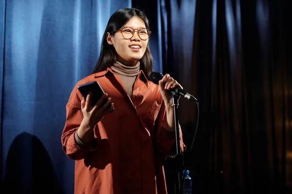 Boldog Fiatal Női Humorista Okostelefonnal Mikrofonnal Színpadon Közönség Előtt Hangsúlyos Stock Fotó