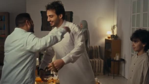 在Kurtas拥抱的快乐的伊斯兰男性亲属相互问候并在家中团聚庆祝开斋节或乌拉扎 巴拉姆的侧影 — 图库视频影像